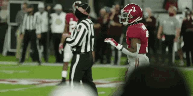 a referee is talking to a football player on the field .