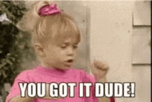 a little girl in a pink shirt is holding her fist up and saying `` you got it dude ! ''