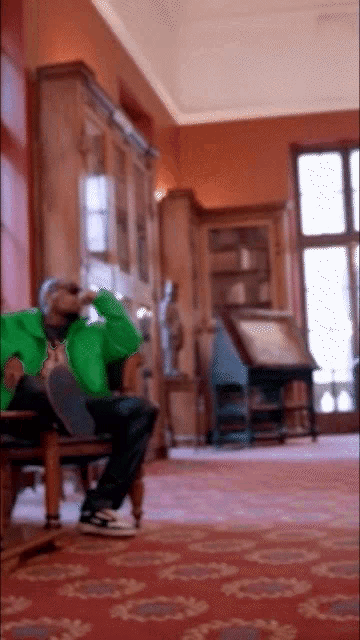 a man in a green jacket sits on a chair