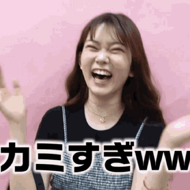 a woman is laughing in front of a pink background with chinese writing