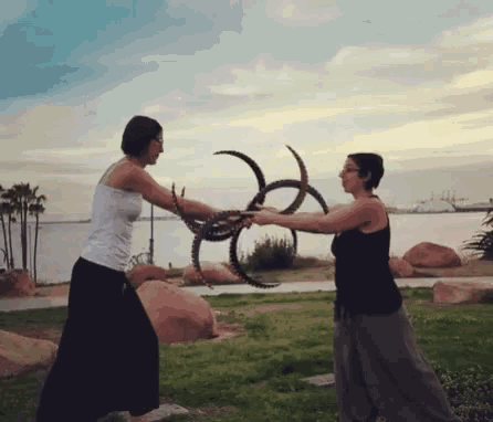 two women are holding a sculpture in their hands in a park