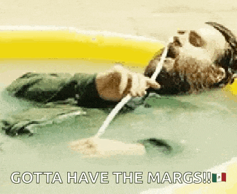 a man with a beard is laying in a bathtub holding a straw in his mouth .