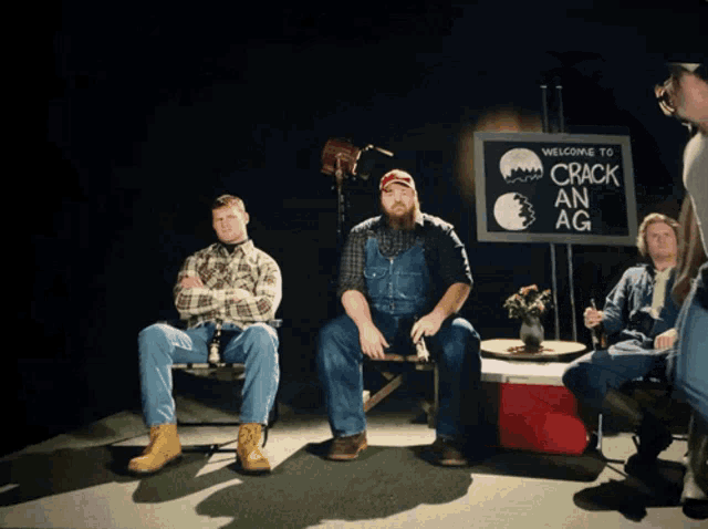 a group of men are sitting in front of a sign that says welcome to crack an ag