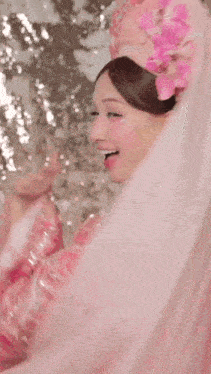 a woman in a pink dress is smiling and holding an umbrella in her hands .