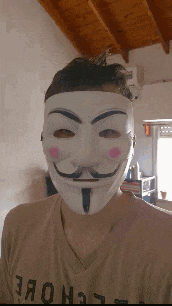 a man wearing a anonymous mask and a t-shirt that says techne