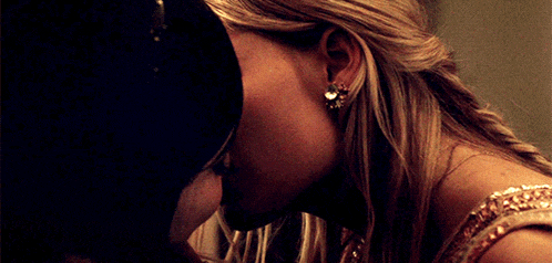 a close up of two women kissing with one wearing a gold earring