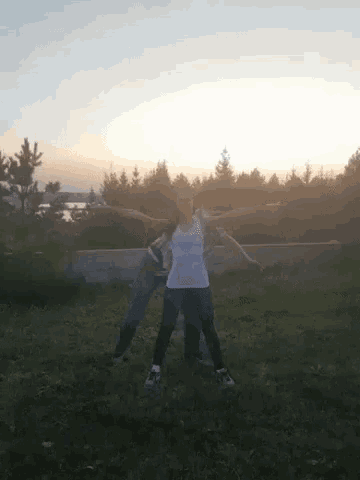 a couple of people are standing in a field with their arms outstretched