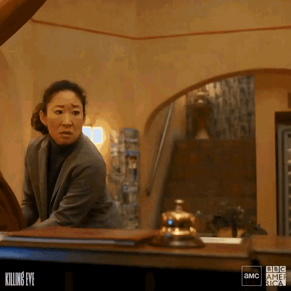 a woman in a suit is standing in front of a bbc america ad