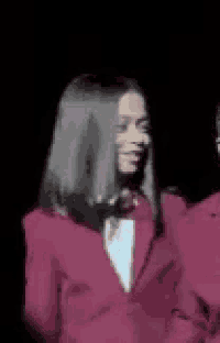 a woman in a pink suit is standing next to another woman .