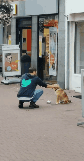 a man kneeling down petting a dog outside a store