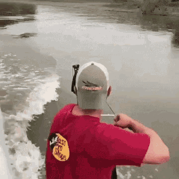 a man wearing a red bass pro shops shirt is fishing