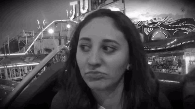 a black and white photo of a woman in front of a roller coaster that says ' turm ' on it