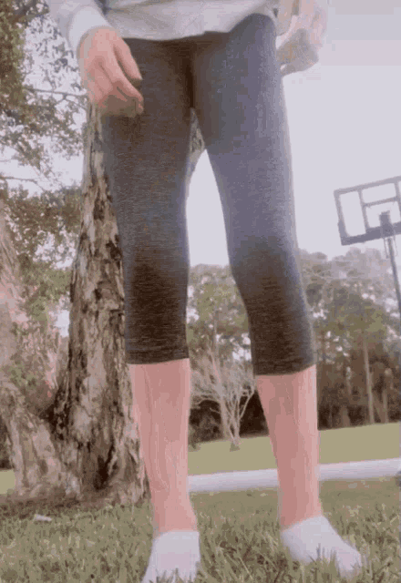 a person wearing gray leggings and white socks is standing in the grass