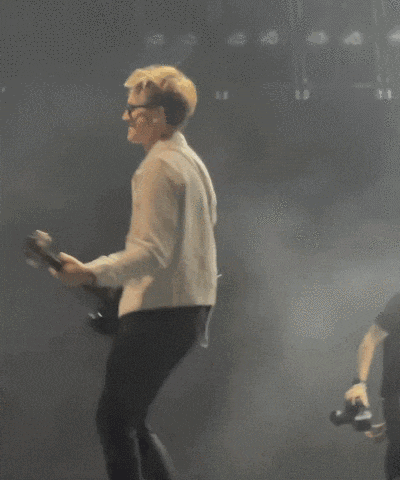 a man in a white jacket playing a guitar on stage