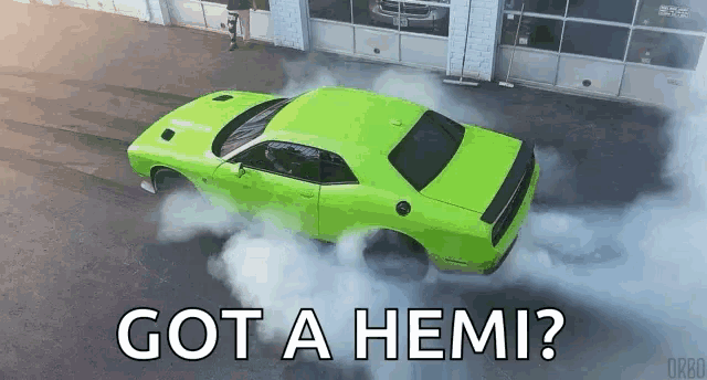 a green dodge challenger is doing a burnout in front of a garage with the words `` got a hemi ? ''
