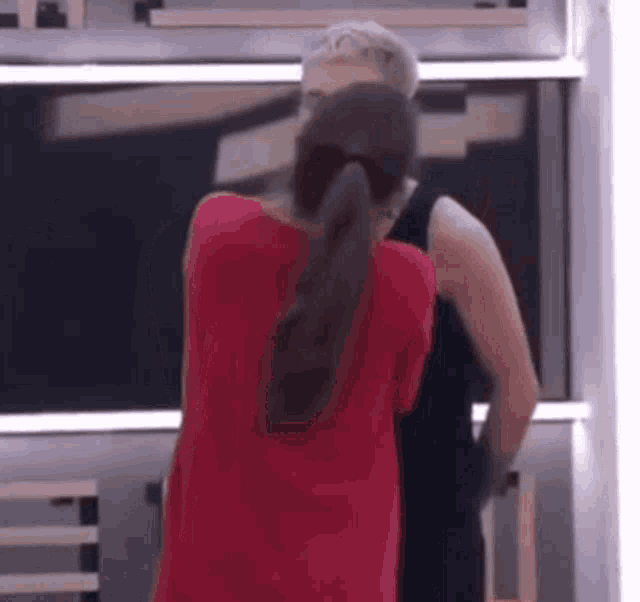 a man and woman are standing next to each other in a room . the woman is wearing a red shirt .