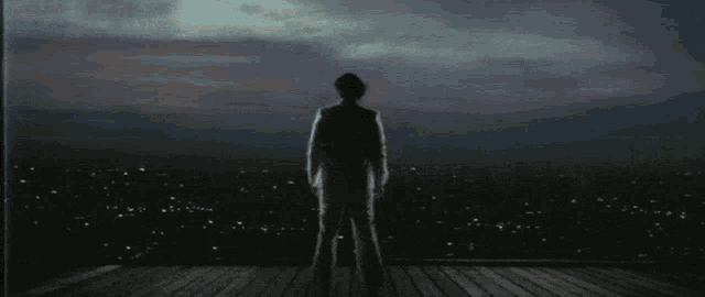 a man in a suit and hat stands in front of a city at night .