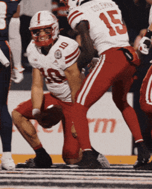 a football player with the number 10 on his jersey is squatting down