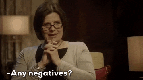 a woman is sitting in a chair with her hands folded and says - any negatives ?