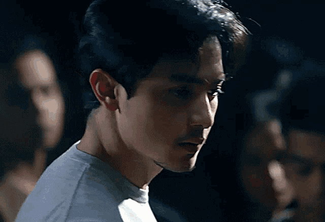 a man in a white shirt is standing in a dark room