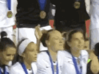 a group of women are sitting in a stadium wearing medals and headbands
