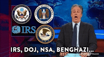 a man in a suit and tie stands in front of logos for the irs and the national security agency
