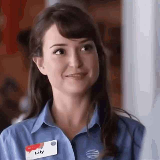 a woman wearing a blue shirt and name tag is smiling .