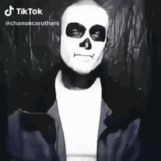 a man wearing a skeleton mask and a blue jacket is making a funny face .