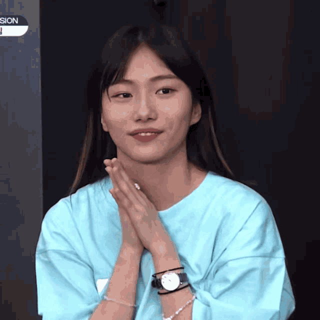a woman wearing a blue shirt and a watch with the word sion on the bottom right