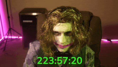 a man in a joker costume is sitting in front of a timer that reads 223:57-20