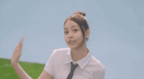 a girl in a white shirt and blue skirt is dancing on a grassy hill