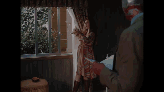 a man and a woman are standing in front of a window .