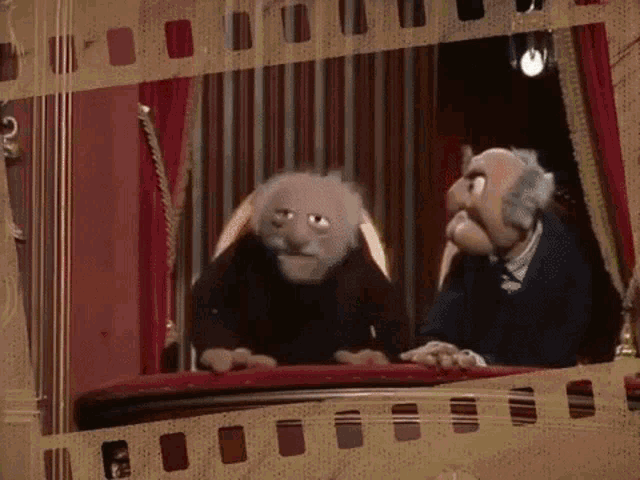 two muppets are sitting next to each other on a stage in a theater .