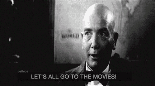 a bald man in a tuxedo and bow tie is talking about going to the movies .