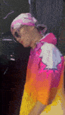 a man wearing a pink hat and sunglasses is standing in a room .