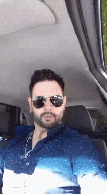 a man with a beard wearing sunglasses and a blue shirt
