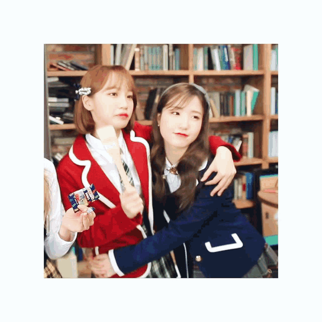 a girl in a red jacket is hugging a girl in a blue jacket with the letter l on it