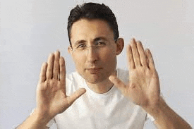 a man in a white shirt is making a stop sign with both hands .