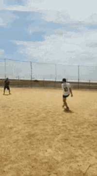 a man in a blue shirt is standing on a dirt field