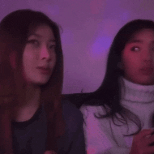 two women are sitting next to each other in a dark room .