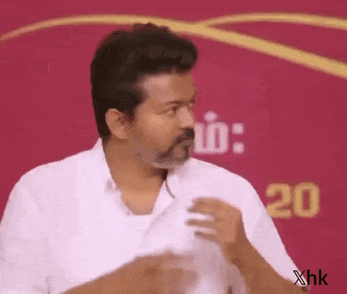 a man in a white shirt is standing in front of a red background and making a funny face .