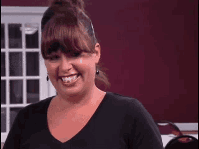 a woman wearing a black shirt and earrings smiles for the camera