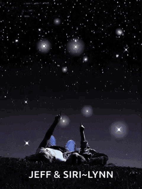 a man and a woman are laying in the grass pointing at the stars .