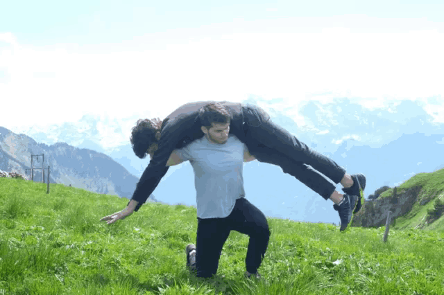 a man carrying another man on his shoulders in a field