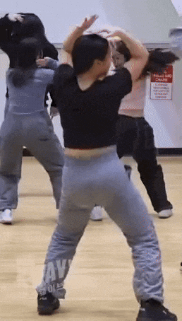 a group of people are standing on a wooden floor dancing .