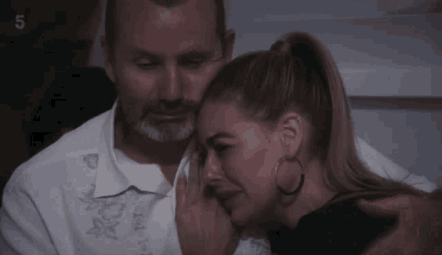 a man and a woman are hugging with the number 5 on the bottom right