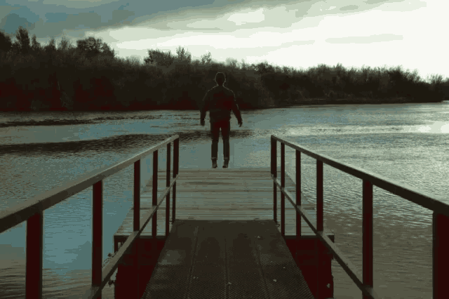 a man stands on a dock overlooking a lake