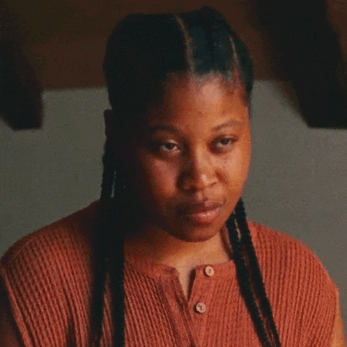 a woman with braids is wearing a brown shirt with buttons
