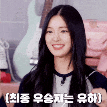a girl with long black hair is smiling in front of a guitar and a pink bag