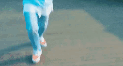 a person wearing a blue shirt and blue jeans is walking down a street .